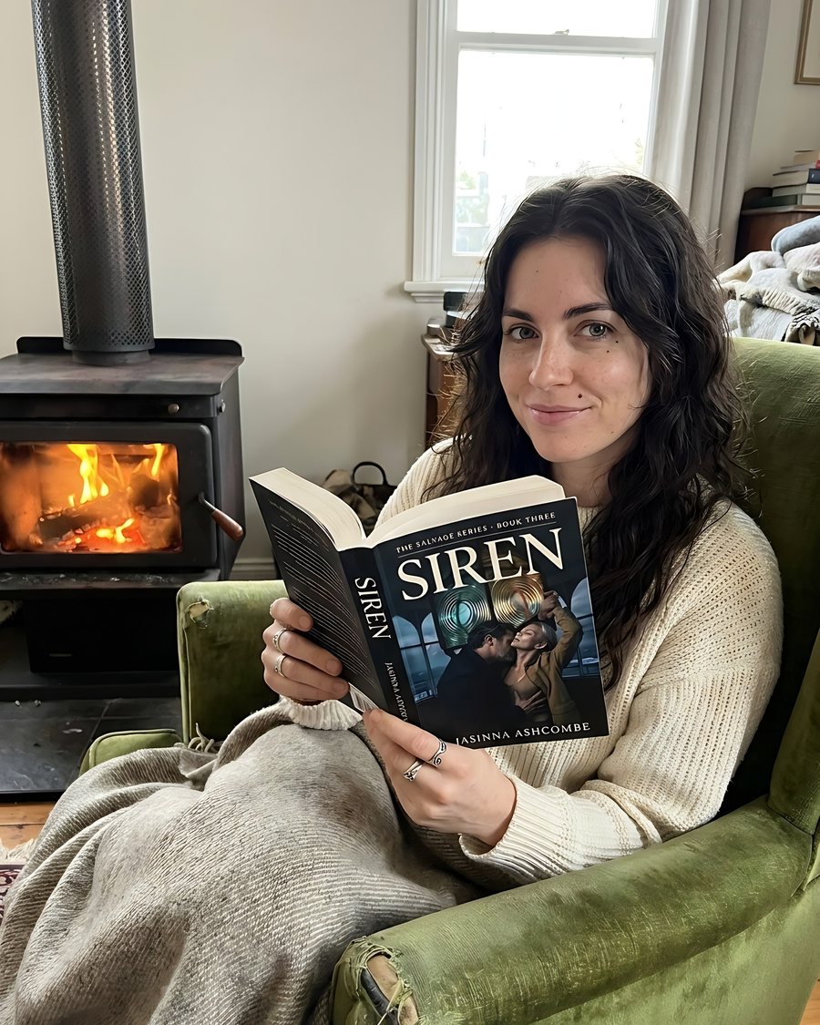 Jasinna Ashcombe reading SIREN in an armchair by the fire
